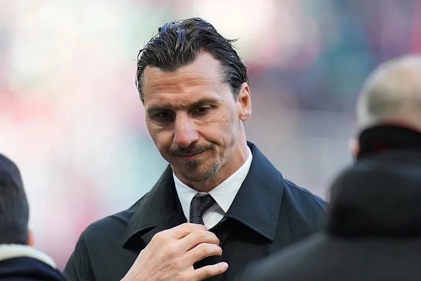 Zlatan Ibrahimovic saat mengenakan setelan jas berdiri di pinggir lapangan Stadion San Siro memperhatikan sesi latihan skuad AC Milan.